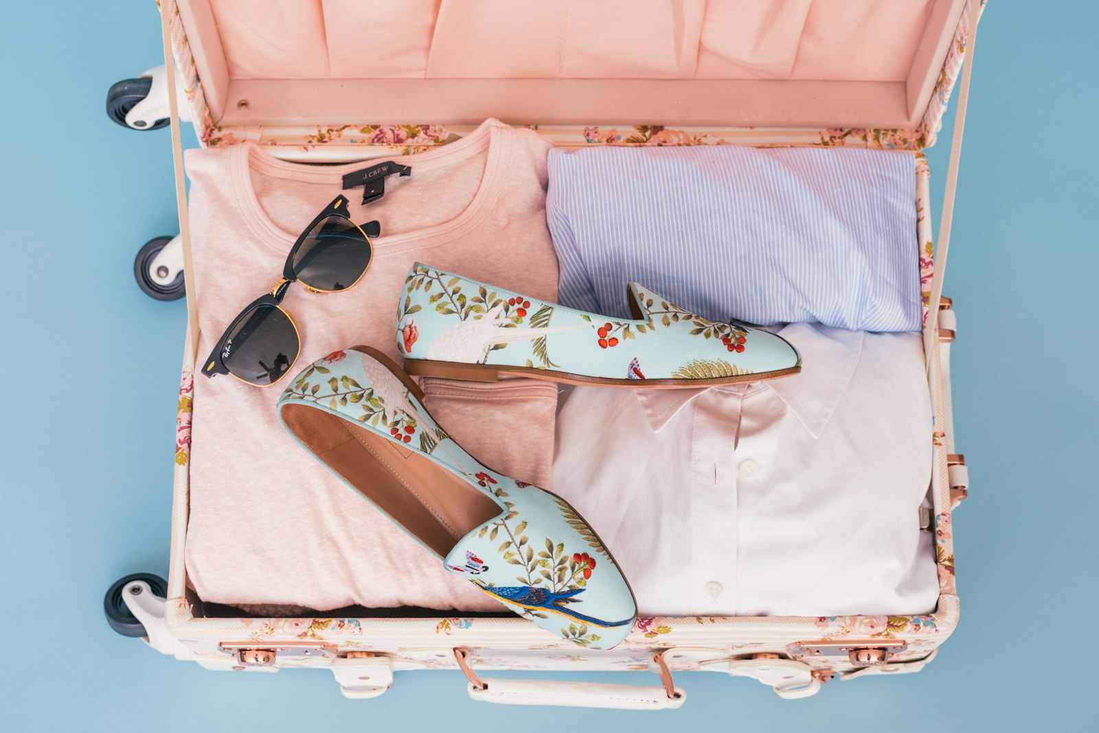Neatly packed open suitcase with folded clothes and sunglasses